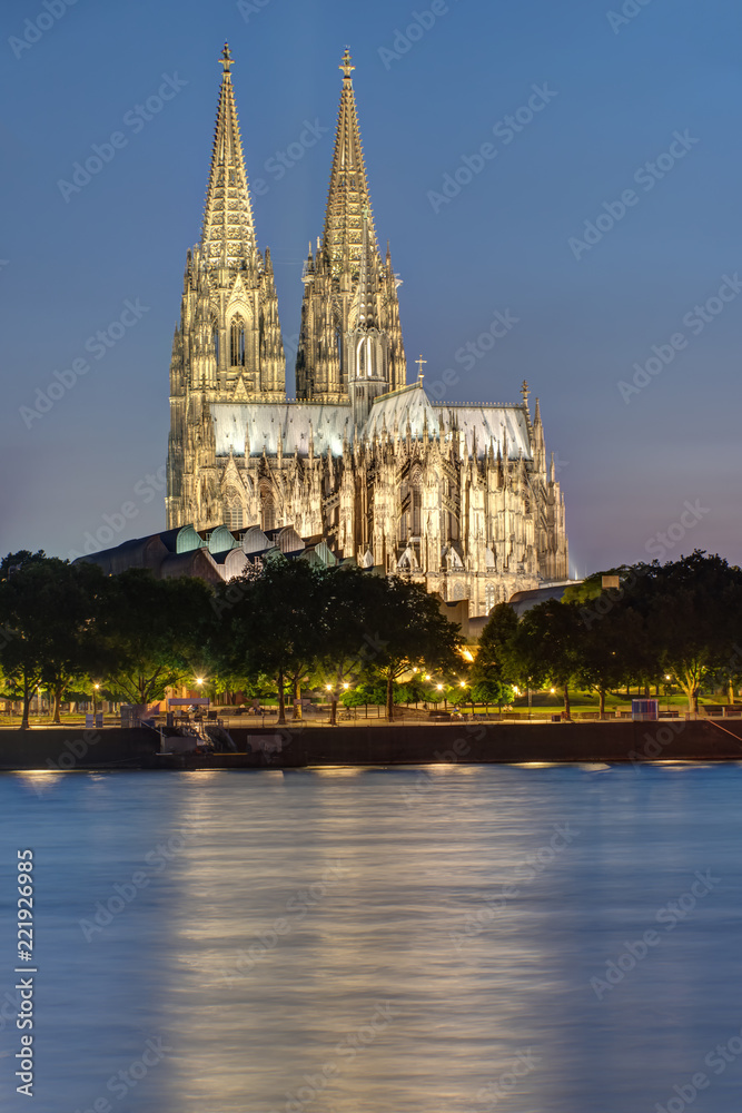 The famous illuminated Koelner Dom with the river Rhine at night