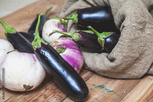 bag of blue eggplants rests on white photo