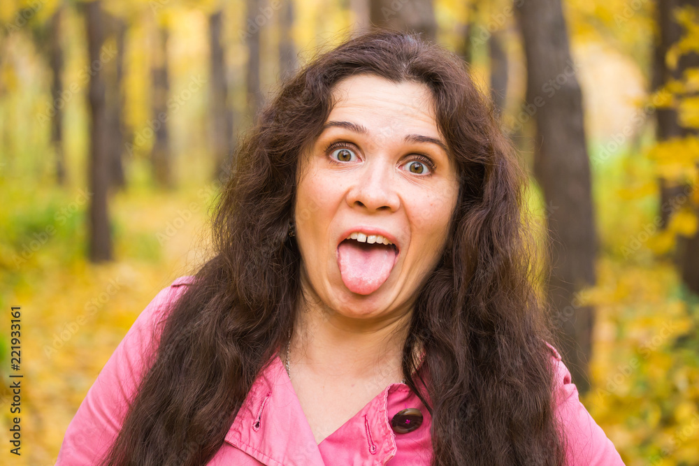 Emotional girl. Beautiful young plus size woman shows tongue in autumn nature Emotional girl. Beautiful young plus size woman shows tongue in autumn nature