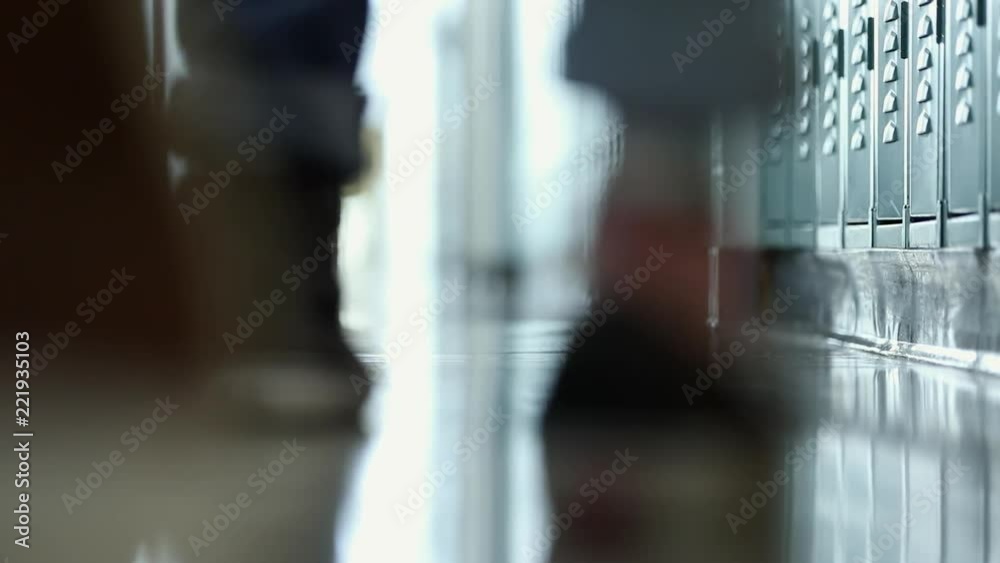View of students feet walking in school hallway past lockers.