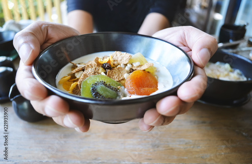 Man Holding muesli bowl, eating breakfast cereals with nuts, pumpkin seeds, oats, dried fruit and yogurt, healthy concept