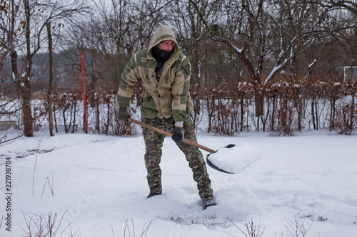 man clears the yard of snow With Shovel. Heavy snowfall in winter. High level of snow. Snowy snowdrift.