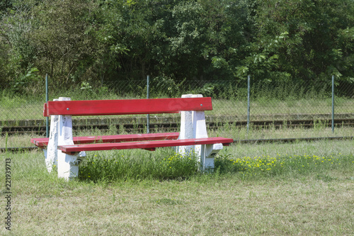 Red bench and yellow flowers at a rural train station in Eastern Europe, Hungary