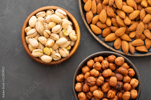 Assorted nuts in bowls on a black background. Copy space.