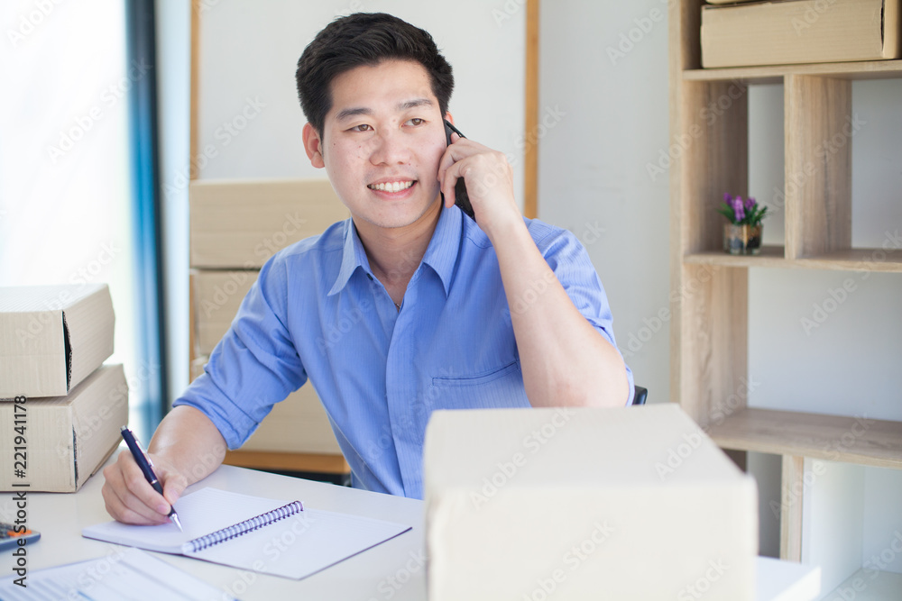  Asia handsome businessman working online shopping , checking and inserting boxes to deliver to the customer. at his home