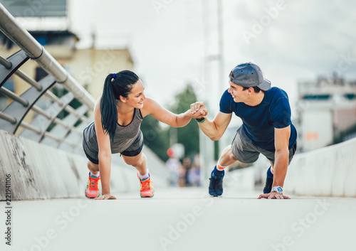 Happy couple doing push-ups outdoors on the bridge