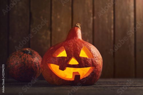 Carved pumpkin as symbol of Halloween and candles on wooden background photo