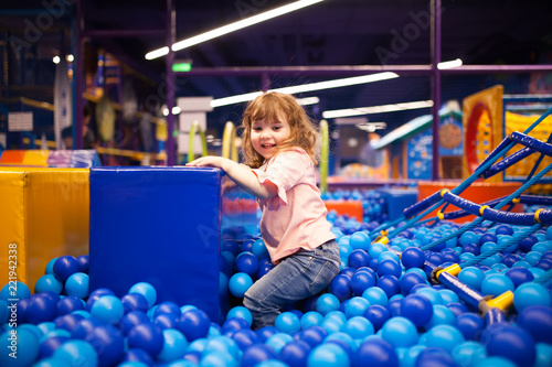 Happy little girl child in colourful blue plastic balls pool.