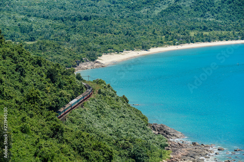 A passenger train passes along lush coastal Vietnam on a beautiful, sunny day