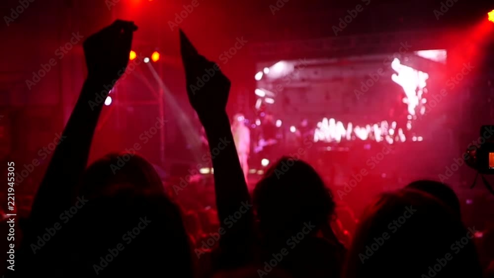 Girls fan silhouettes in a concert audience enjoying a music performance in lumiere