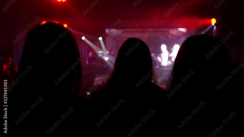 Girls fan silhouettes in a concert audience enjoying a music performance in lumiere