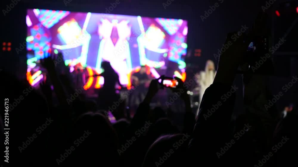 Dancing crowd fan spectators cheerfully jumping shooting phones in lumiere