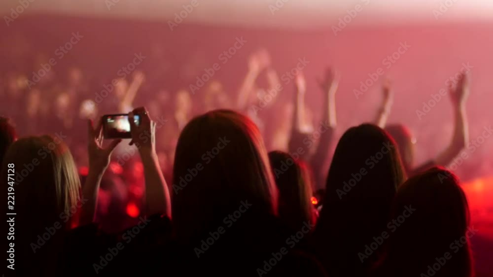 Dancing cheering crowd fan spectators rais hands at concert lumiere by stage