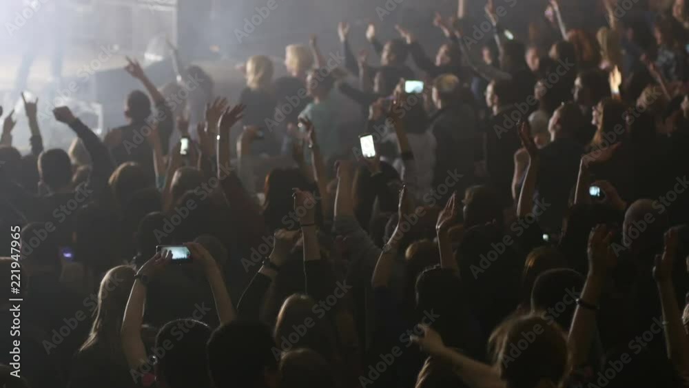 Crowd fans people dancing jumping raise hands at music concert lumiere lights