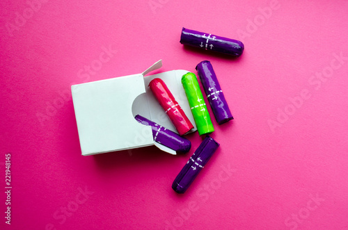  white box with multi-colored tampons on a pink background photo