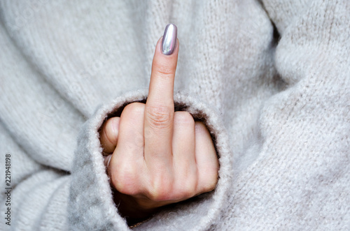 фотографія a woman in a sweater shows a gesture of fuck you
