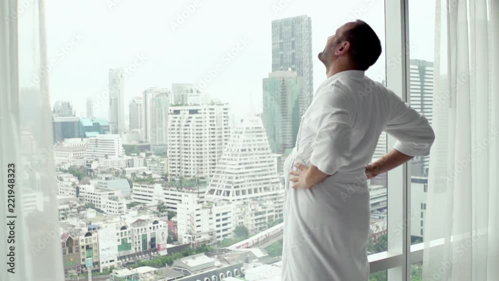 Handsome man in bathrobe admire city standing by the window, super slow motion
Handsome man in bathrobe admire city standing by the window, super slow motion