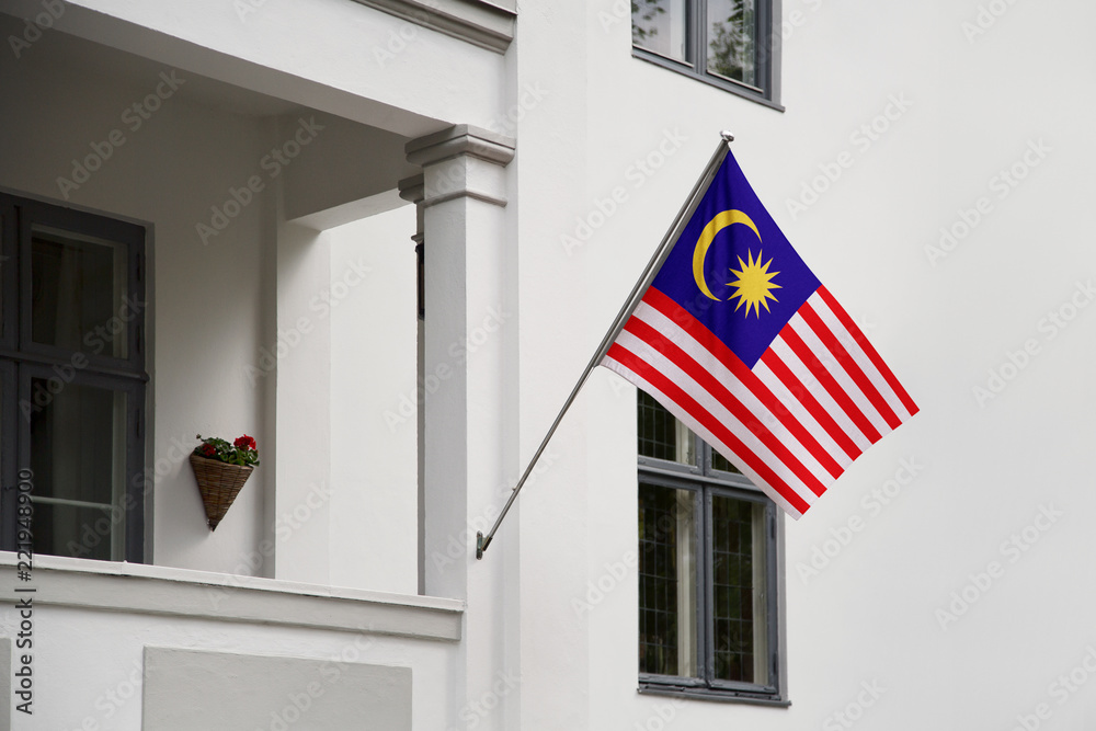 Malaysia flag.  Malaysia flag hanging on a pole in front of the house. National flag of waving on a home displaying on a pole on a front door of a building. Flag raised at a full staff.