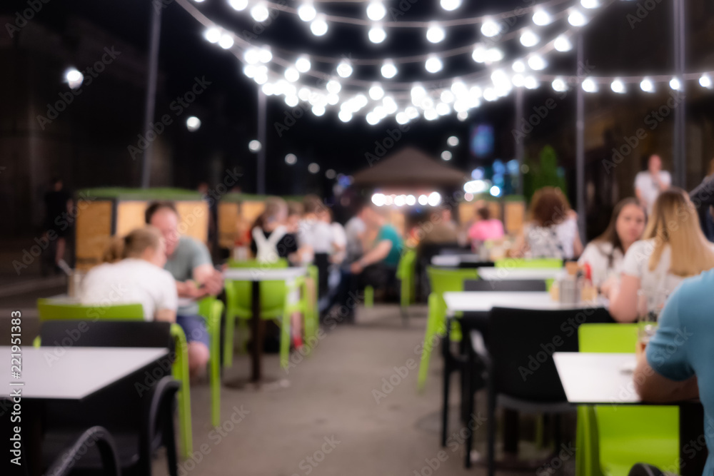 Abstract blurred image of night festival in a restaurant. Happy and relaxing people at the cafe table
