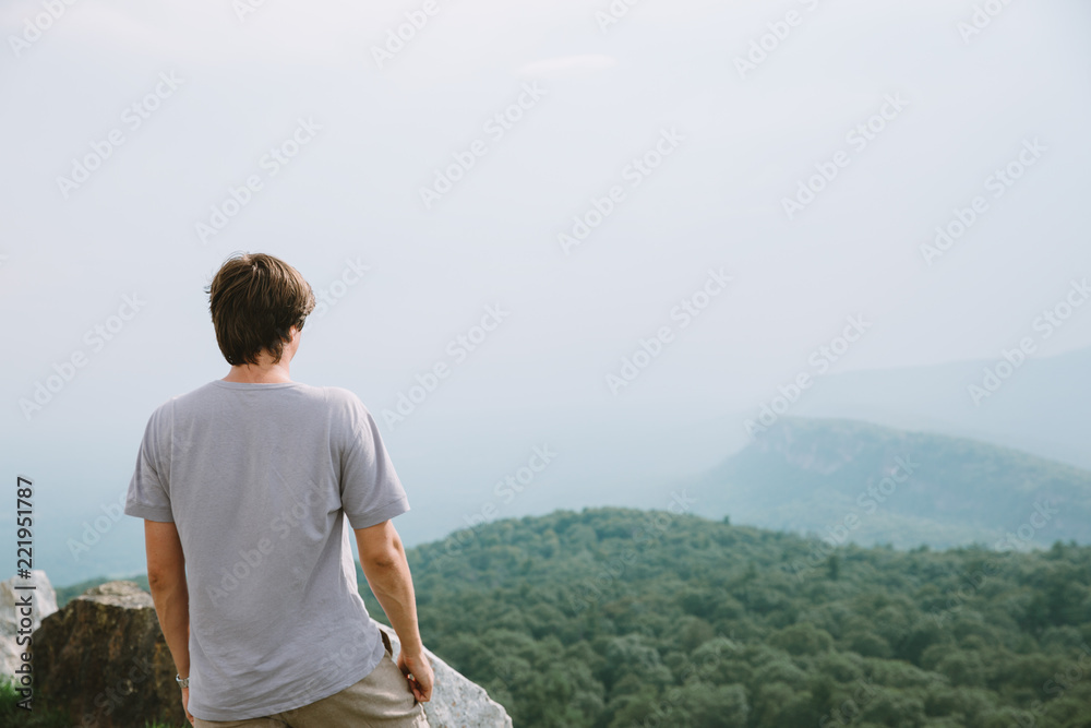 young man standing on the edge of mountains