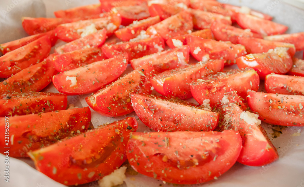 The manufacturing process of sundried tomatoes cut into slices sprinkled with salt, oregano, Basil, thyme being dried out in the sun or in the oven Close-up, selective focus. The manufacturing process of sundried tomatoes cut into slices sprinkled with salt, oregano, Basil, thyme being dried out in the sun or in the oven Close-up, selective focus.