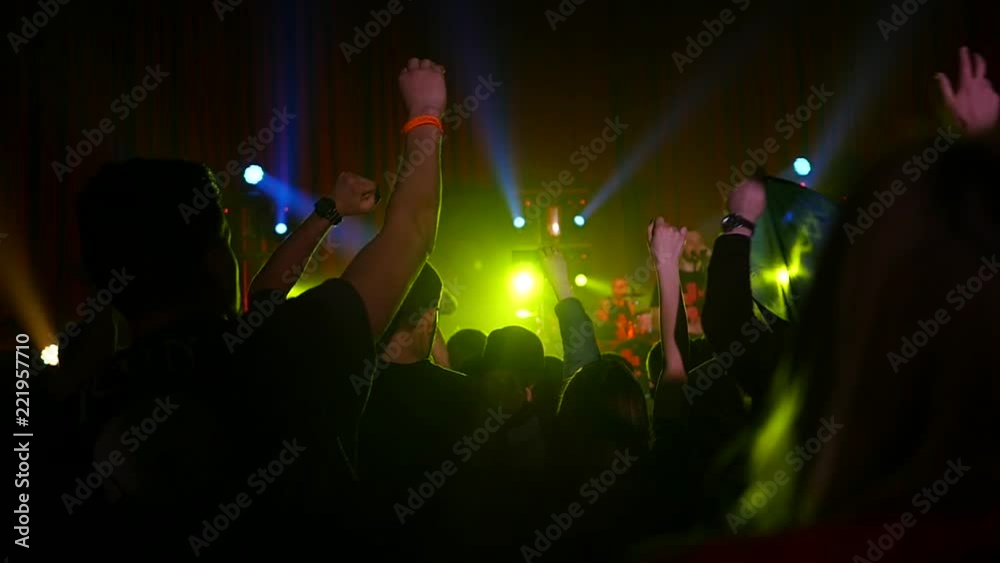Crowd fan spectators silhouettes rais hands dancing jumping at concert in lumiere