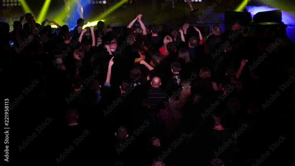 Dancing cheering crowd fan spectators rais hands at concert lumiere spot lights