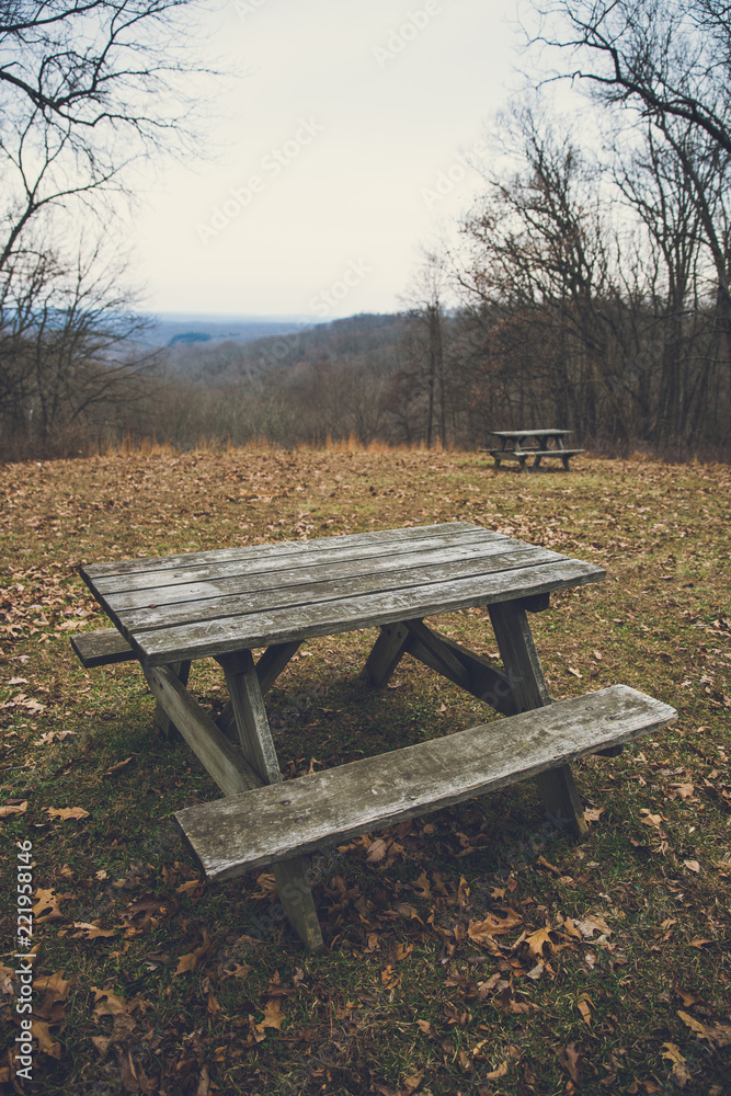 Vintage Wooden Picnic Table in Park with Rolling Hills on a Grey Winter Day.