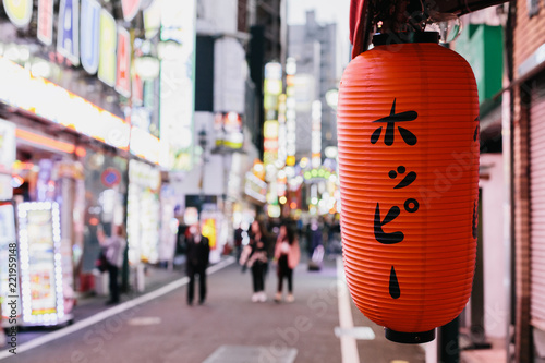 A lantern in front of a bar on a street full of neon lights in Tokyo's red light district called Kabukicho. photo