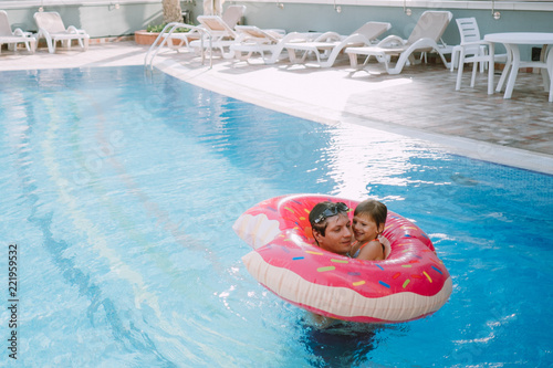 father with daughater swim with inflatable donut in the swimming pool photo