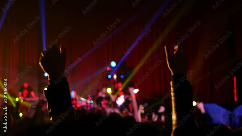 Cheering spectator silhouette at flashing lumiere raise and clap with hands
