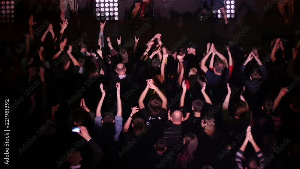 Crowd fan spectators cheerfully clapping hands up in air at concert flash lumiere