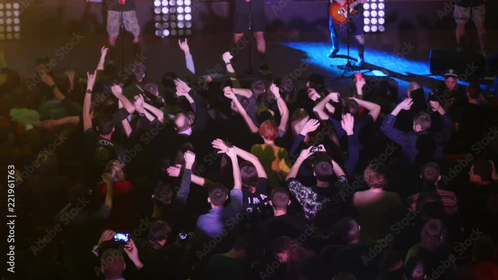 Crowd fan spectators cheerfully sway hands up in air at concert flash light lumiere