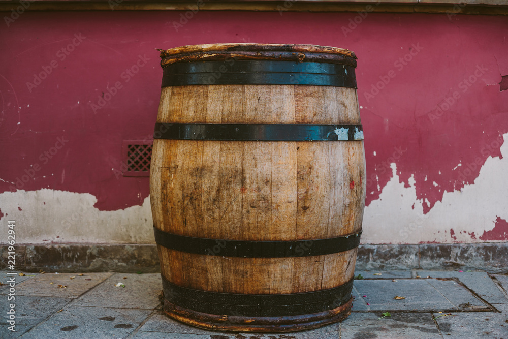 an oak barrel with wine, against the background of the old wrapped wall an oak barrel with wine, against the background of the old wrapped wall