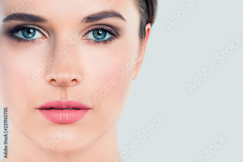 Beautiful female face closeup on white background with copy space. Young woman with perfect makeup