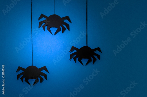 Black paper spider with web on dark blue background. Halloween concept. Paper cut style. Top view