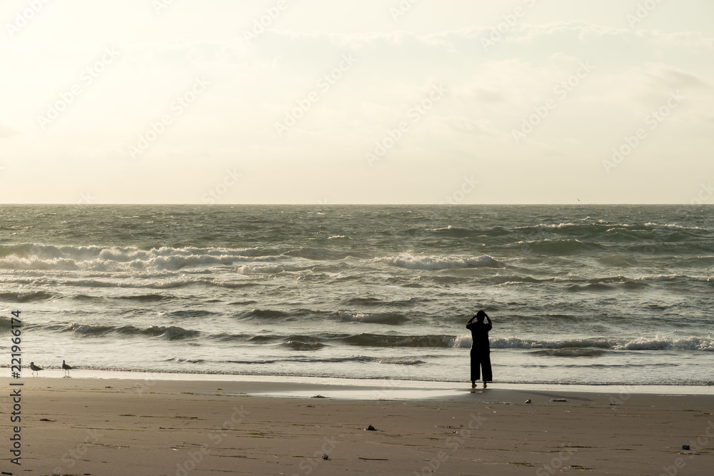 朝焼けの海岸を歩く女性 / リラックスイメージ