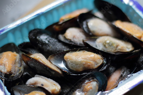 Heap of frozen cooked mussel meat in a box from supermarket, seafood 