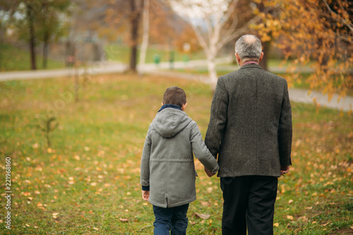 Grandpa and his grandson are walking in the park. The spend time together