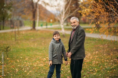 Fototapeta Naklejka Na Ścianę i Meble -  Grandpa and his grandson are walking in the park. The spend time together