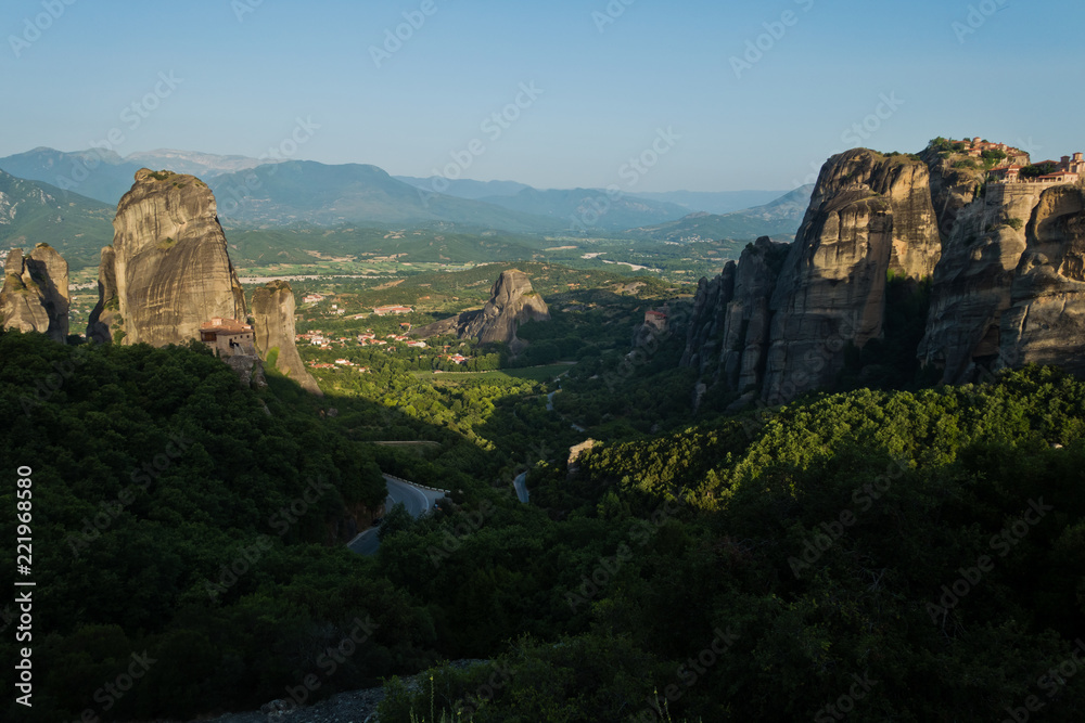 Huge rocks with christian orthodox monasteries at sunrise with Meteora valley in background near Kalambaka, Thessaly, Greece