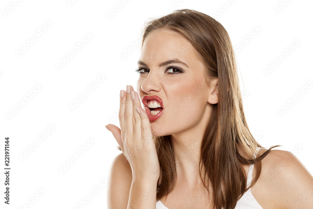 Beautiful girl checking her breath on white background Beautiful girl checking her breath on white background