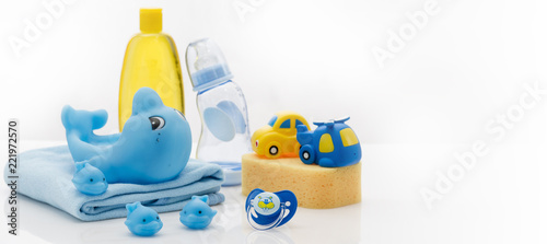 Still life with baby hygiene and bath items, shampoo bottle, essential oil, baby soap, towel, pacifier, rubber toy, shower puff. Copy space for your text