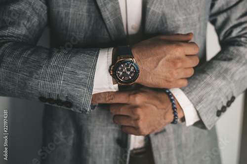 Businessman luxury style. Men style.closeup fashion image of luxury watch on wrist of man.body detail of a business man.Man's hand in a grey shirt with cufflinks in a pants pocket closeup. Toned photo