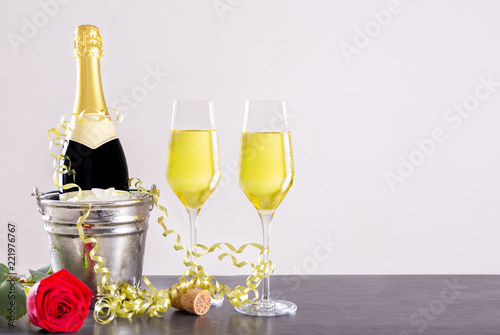 Champagner Flasche im Sektkühler mit einer Rose und goldenen Luftschlangen