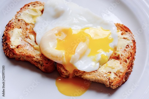 Poached egg on brown buttered toast  photo