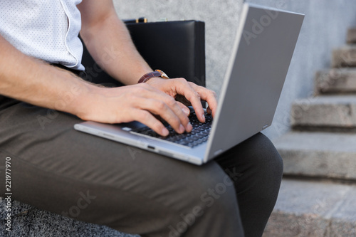 Cropped image of business man with briefcase using laptop computer