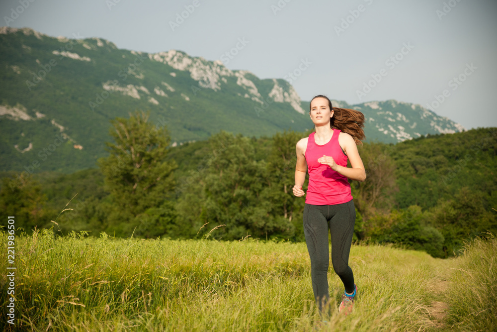Beautiful young woman workout outdoor runs across meadow in early summer