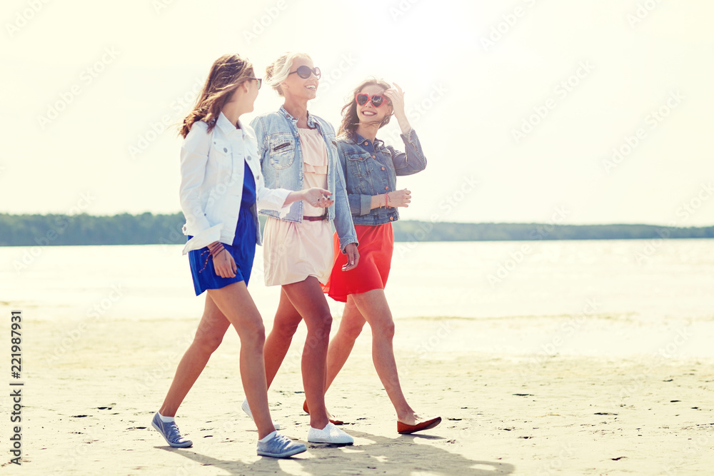 summer vacation, holidays, travel and people concept - group of smiling young female friends in sunglasses and casual clothes walking along beach summer vacation, holidays, travel and people concept - group of smiling young female friends in sunglasses and casual clothes walking along beach