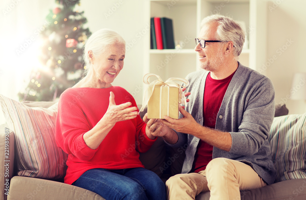 christmas, holidays and people concept - happy smiling senior couple with gift box at home christmas, holidays and people concept - happy smiling senior couple with gift box at home